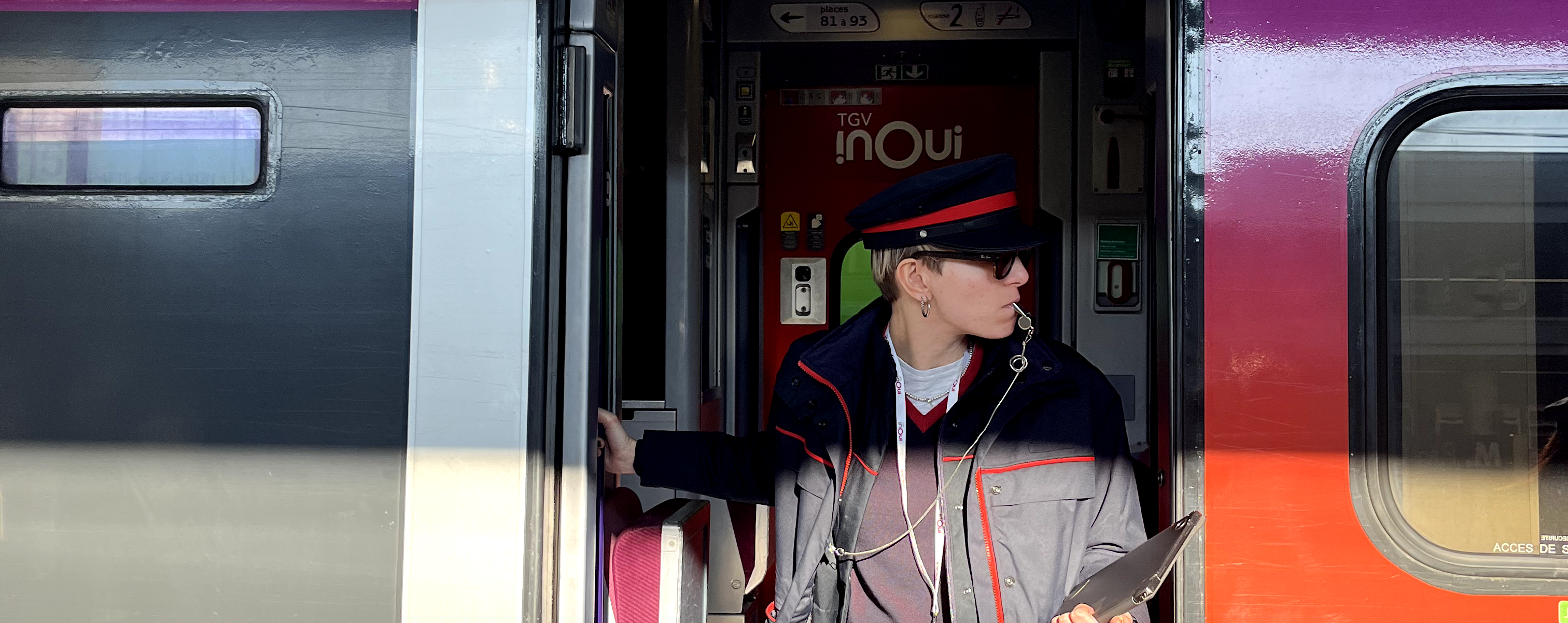 Capotreno TGV INOUI con fischietto, in uniforme ufficiale, all'ingresso di un treno ad alta velocità pronto per partire.