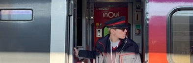Capotreno TGV INOUI con fischietto, in uniforme ufficiale, all'ingresso di un treno ad alta velocità pronto per partire.
